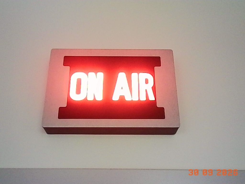 "On Air Sign"
A rectangular sign with a black background and the words "On Air" lit up with red lights.